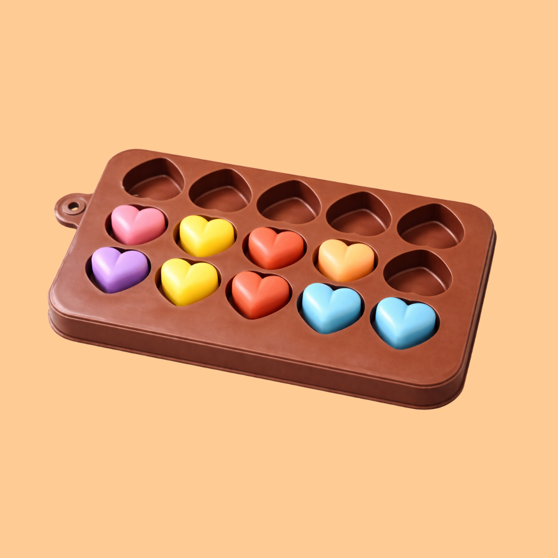 Brown silicone heart cavity mold partially filled with colorful heart shaped soaps in different pastel colors, flexible silicone mold used for handmade soap crafting, DIY bath products, wax melts, and cosmetic soap production.