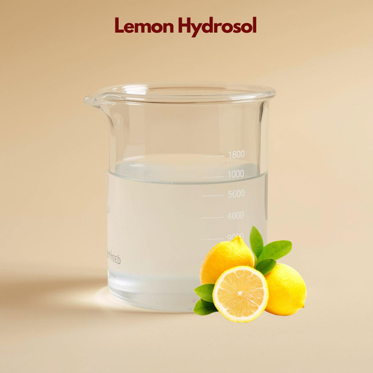 Glass beaker containing clear liquid labeled Lemon Hydrosol with whole and sliced lemon illustrations and green leaves. This lemon hydrosol facial mist is presented as a clarifying and refreshing citrus floral water for skin.