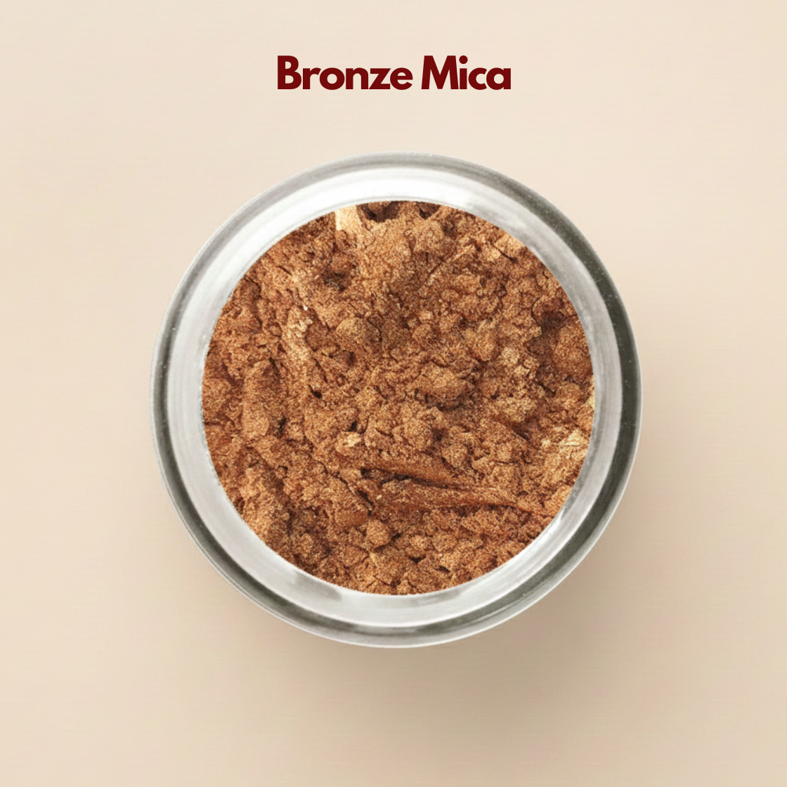 Top view of bronze mica powder inside a round clear container, showing shimmering metallic brown flakes with a reflective mineral surface. The texture appears slightly crinkled with visible light catching highlights across the pigment. This bronze mica powder for cosmetics adds shimmer and dimension to makeup, soap and skincare formulations.