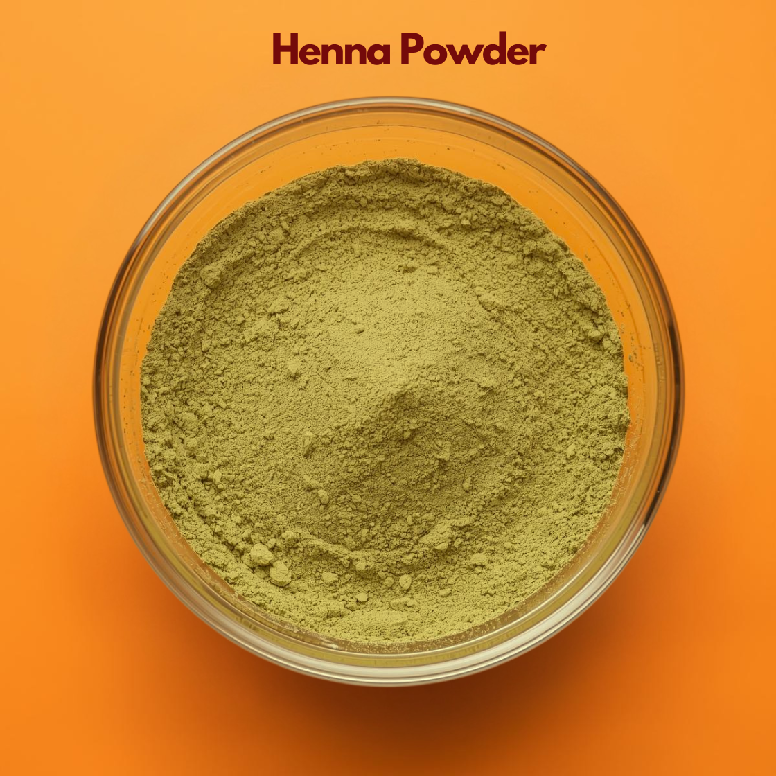 Overhead close up of Henna Powder in a clear glass bowl, featuring light green finely ground herbal powder on a bright orange surface. Pure plant based henna powder used for natural hair dye, scalp conditioning and Ayurvedic hair care formulations.