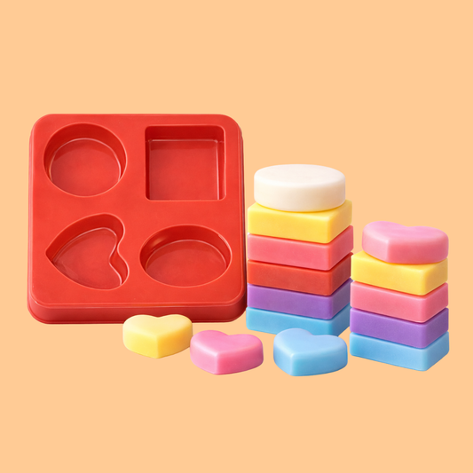 Red silicone multi shape soap mould tray displayed beside stacked colorful handmade soap bars and heart shaped soaps, flexible mold used for melt and pour soap making, DIY soap crafting and artisan bath product production.
