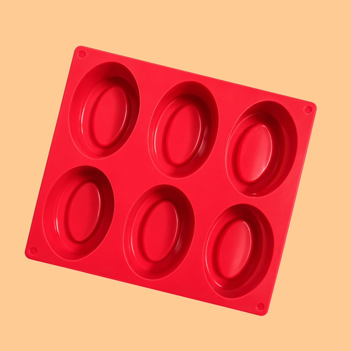 Red silicone soap mould tray with six oval cavities displayed on neutral background, flexible silicone mold used for handmade soap bars, melt and pour soap making, and artisan cosmetic soap production.