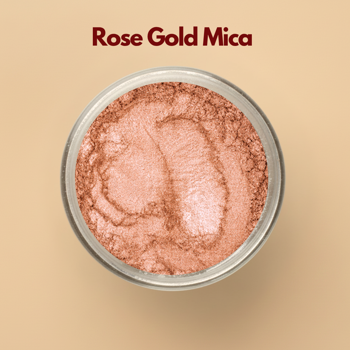 Rose gold mica pigment powder in a transparent cosmetic container with metallic shimmer texture on a beige background. Cosmetic grade mica powder used for soap making, lip gloss, skincare, body shimmer products, makeup formulations, candles, and DIY beauty applications. The image showcases luxurious rose gold shimmer suitable for premium cosmetic product development.