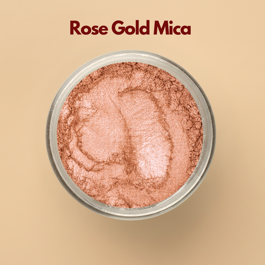 Rose gold mica pigment powder in a transparent cosmetic container with metallic shimmer texture on a beige background. Cosmetic grade mica powder used for soap making, lip gloss, skincare, body shimmer products, makeup formulations, candles, and DIY beauty applications. The image showcases luxurious rose gold shimmer suitable for premium cosmetic product development.