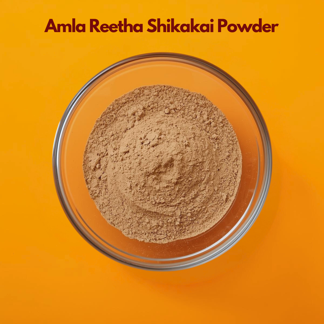 Overhead image of Amla Reetha Shikakai Powder in a clear glass bowl against a bright orange backdrop dark shadow , displaying finely milled light brown herbal blend. Traditional Ayurvedic hair care powder combination used for natural cleansing, strengthening roots, promoting hair growth and herbal shampoo formulations.