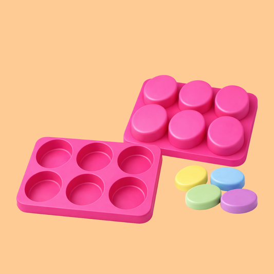 Pink silicone soap mould tray with six oval cavities displayed beside colorful oval handmade soap bars, flexible reusable mold designed for handmade soap making, DIY melt and pour soap crafting, artisan bath product production, and cosmetic soap manufacturing.