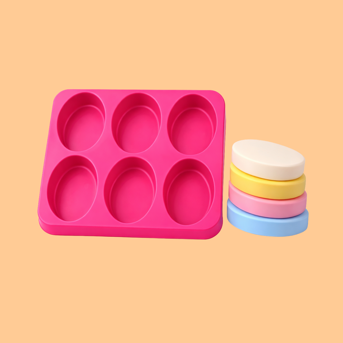 Pink silicone oval cavity soap mould tray shown next to a stack of pastel colored oval soap bars, durable silicone mold used for handmade soap bars, DIY soap crafting, melt and pour soap production and cosmetic bath product manufacturing.