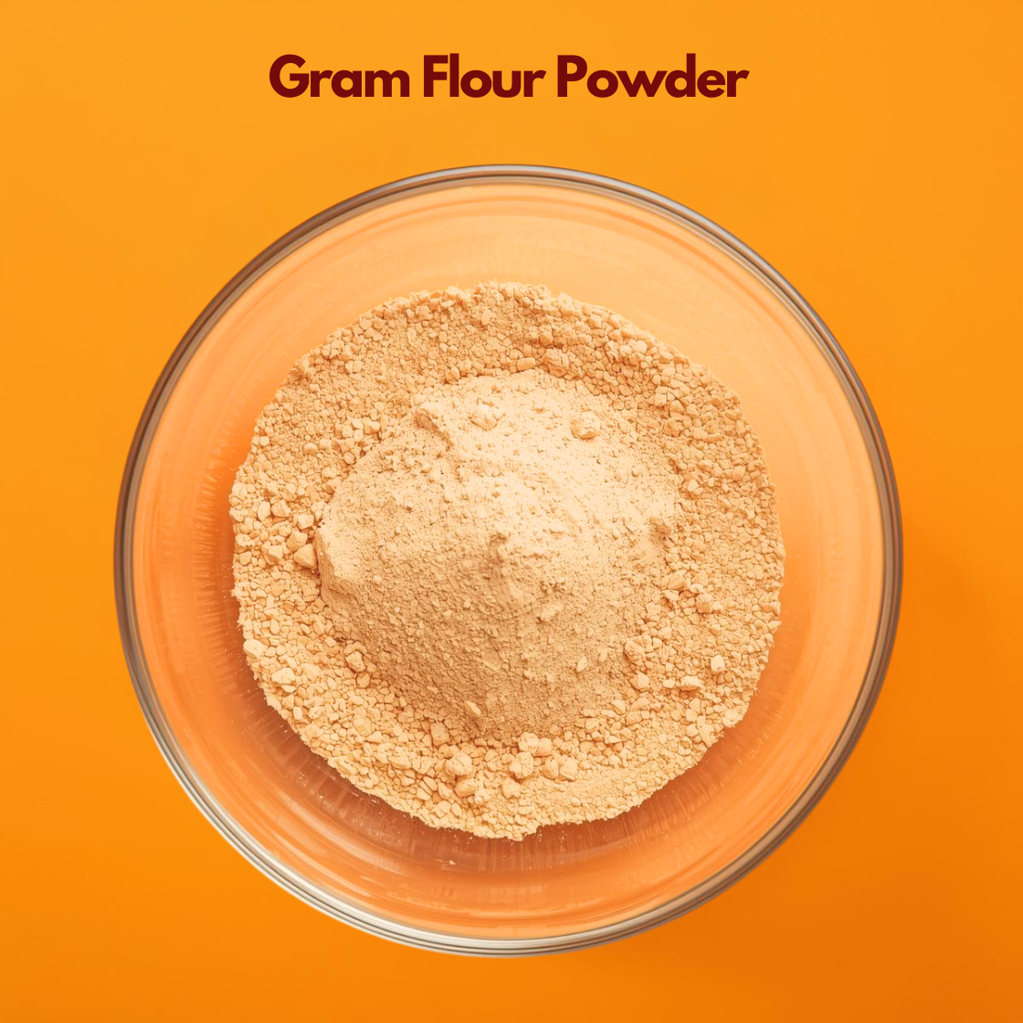  Top angle close up of Gram Flour Powder in a transparent glass bowl placed on a bright orange surface, featuring finely ground pale yellow chickpea flour. Traditional besan powder widely used in natural face masks, exfoliating treatments, and herbal skincare formulations.