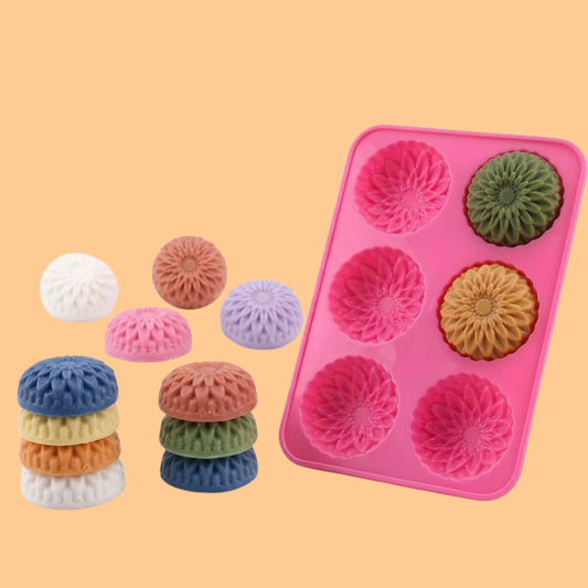 Pink silicone flower soap mold with six decorative floral cavities displayed with colorful finished flower shaped soap bars, silicone mold used for handmade decorative soaps, DIY soap crafting, bath product making and artisan soap production.