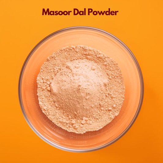 Overhead image of Masoor Dal Powder in a clear glass bowl against an orange background, showing light beige finely milled lentil powder with slightly coarse texture. Natural exfoliating powder used in face packs, skin brightening masks, and Ayurvedic cosmetic applications.
