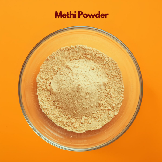 Top view of Methi Powder in a transparent glass bowl against a bright orange backdrop, showing finely ground light beige herbal powder with slightly coarse texture. Fenugreek powder used in herbal hair masks, scalp conditioning treatments and natural cosmetic formulations.