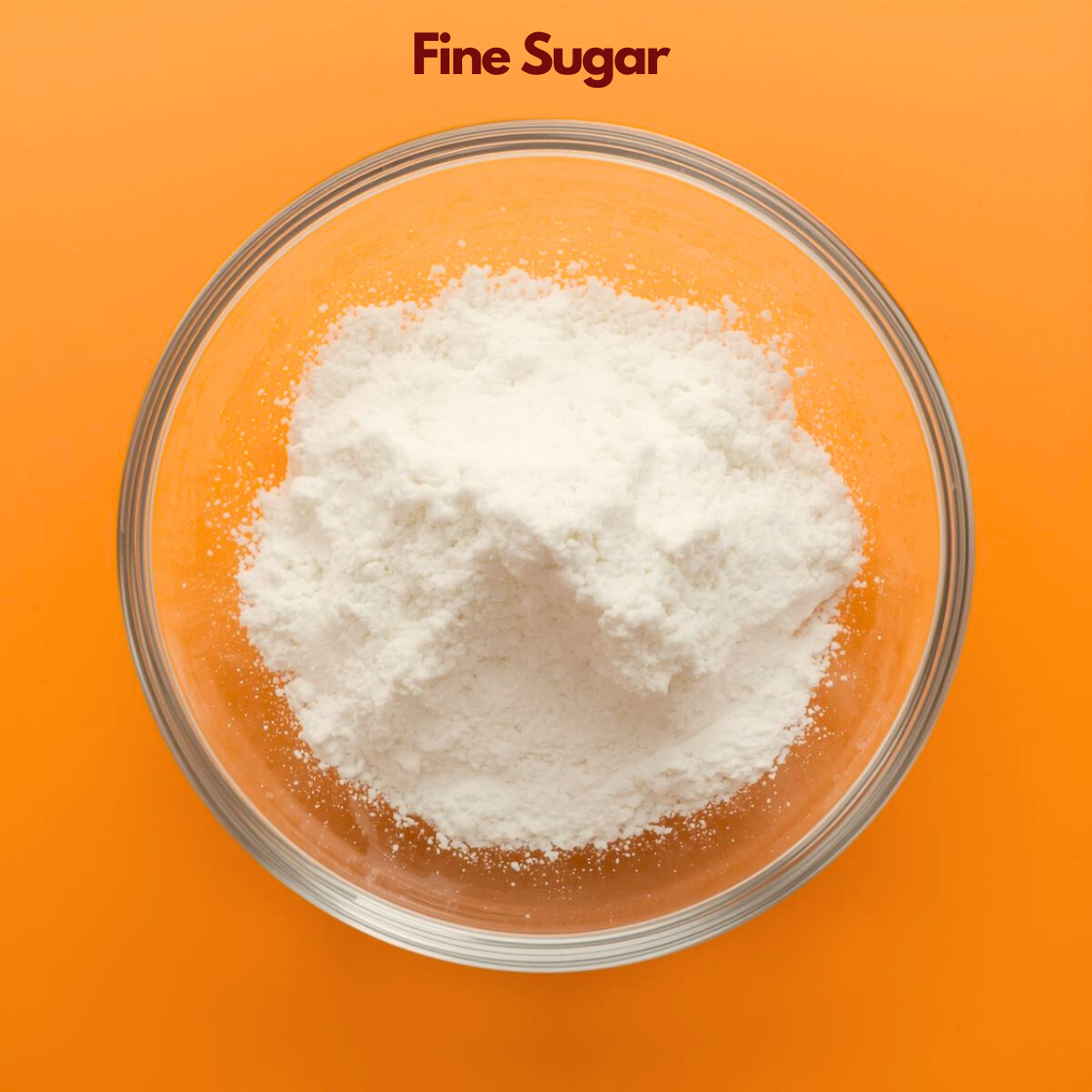  A transparent bowl holds a mound of "Fine White Sugar" crystals arranged in a soft peak against a bright orange background. The granules appear small, slightly sparkling, and evenly textured. Fine sugar is commonly used in cosmetic body scrubs and exfoliating skincare formulations for gentle physical exfoliation.