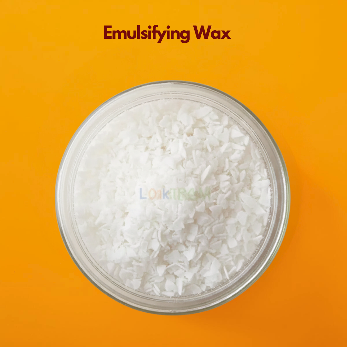  A round glass container holds irregular white wax flakes arranged in a loose pile, photographed from above against a bold orange backdrop. The flakes vary in size and shape, creating a textured surface. Emulsifying wax is a key cosmetic ingredient used in skincare formulations to blend oil and water into stable creams.