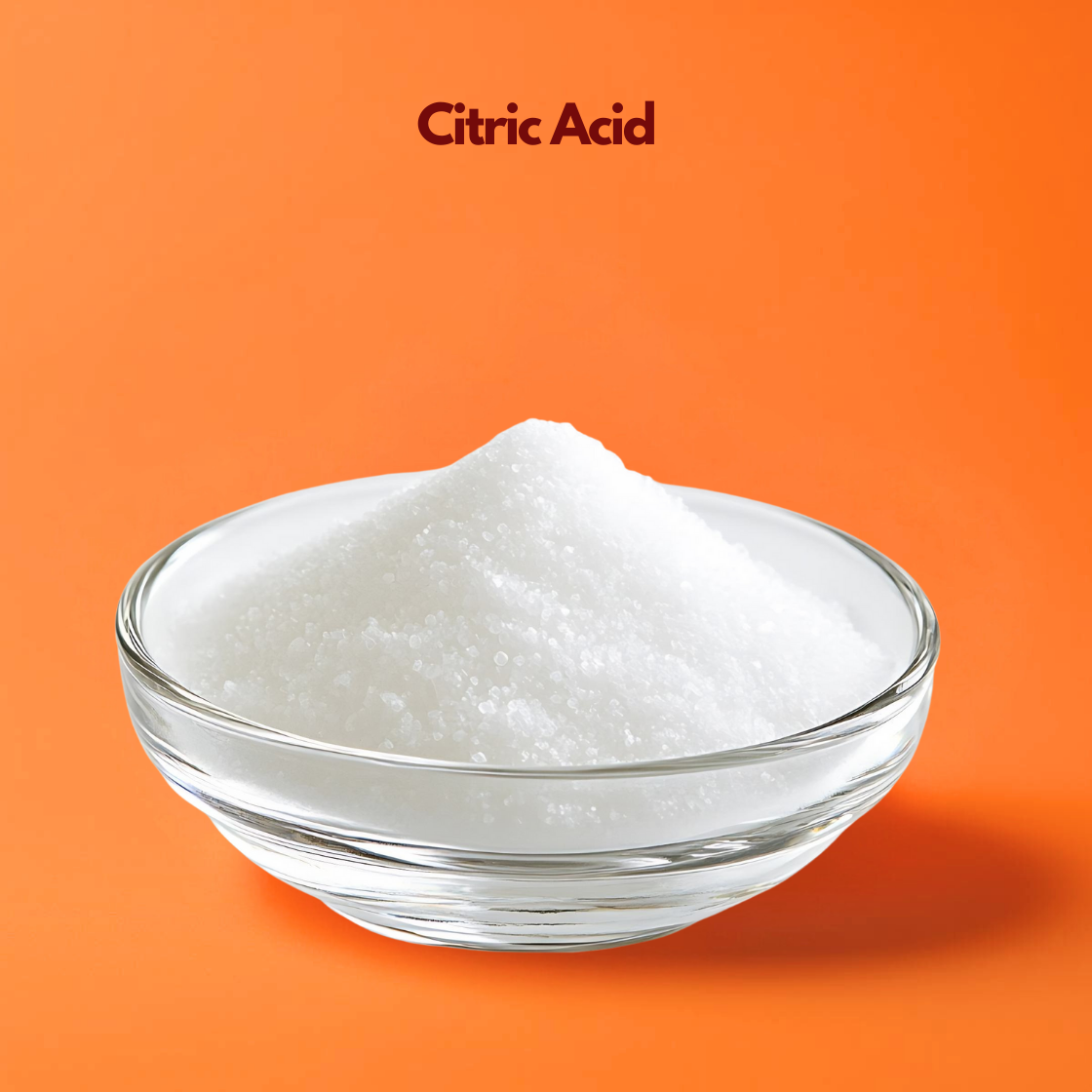 A mound of bright white Citric Acid powder sitting in a clear glass bowl. The powder has a fine, granular and crystalline texture similar to table salt. The bowl is positioned on a clean orange surface. The text "Citric Acid" is centered at the top in a professional maroon font.