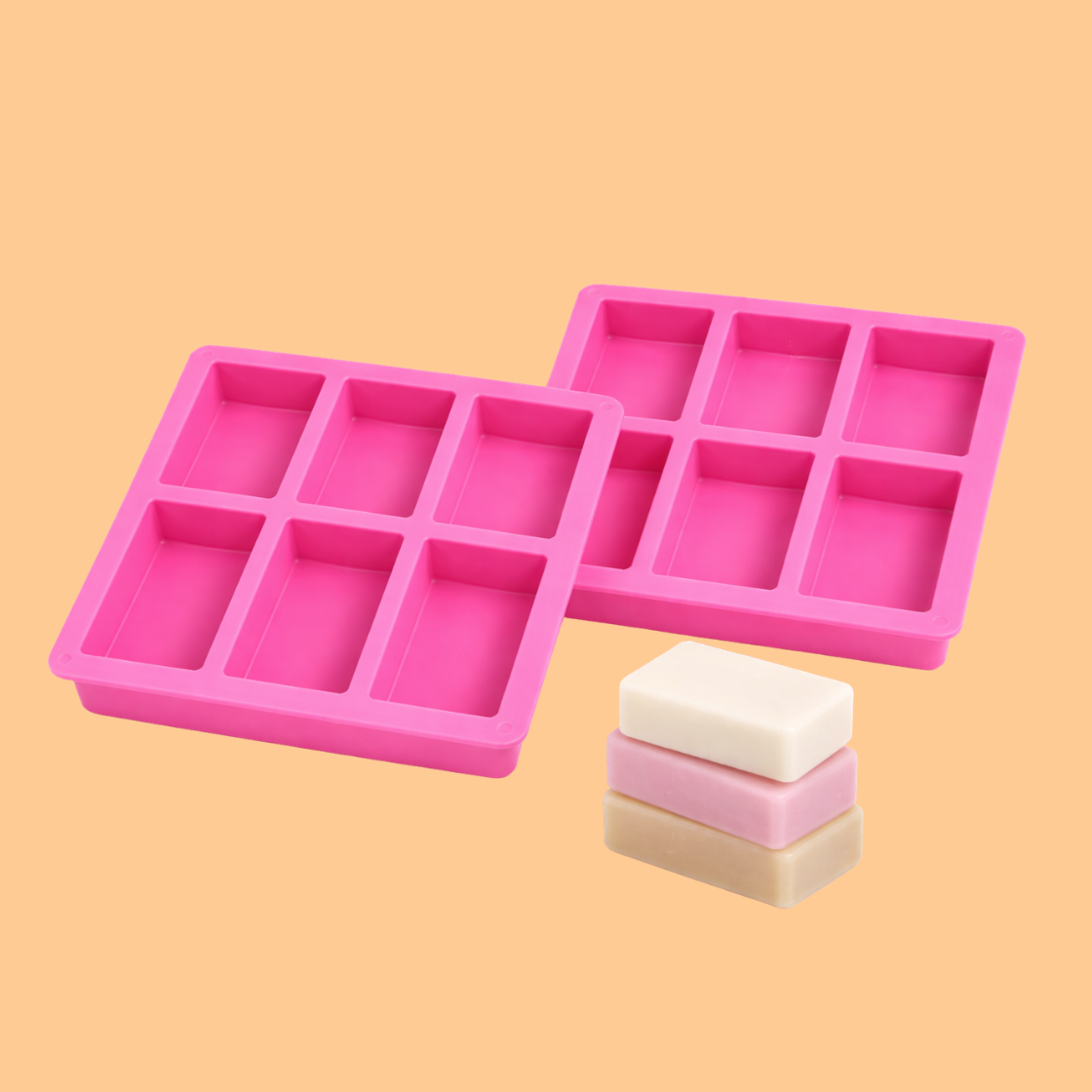 Two pink silicone rectangular soap mould trays displayed with stacked handmade soap bars in different colors, reusable mold used for DIY soap making, bath soap production, and artisan cosmetic soap manufacturing.
