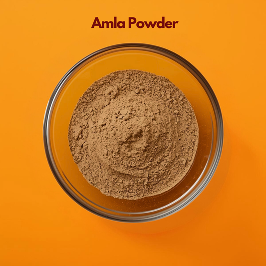Close up of Amla Powder in a transparent glass bowl, displaying its fine light brown texture evenly spread against an orange background. Ayurvedic herbal powder widely used in natural hair care formulations, scalp nourishment masks and herbal skincare blends.