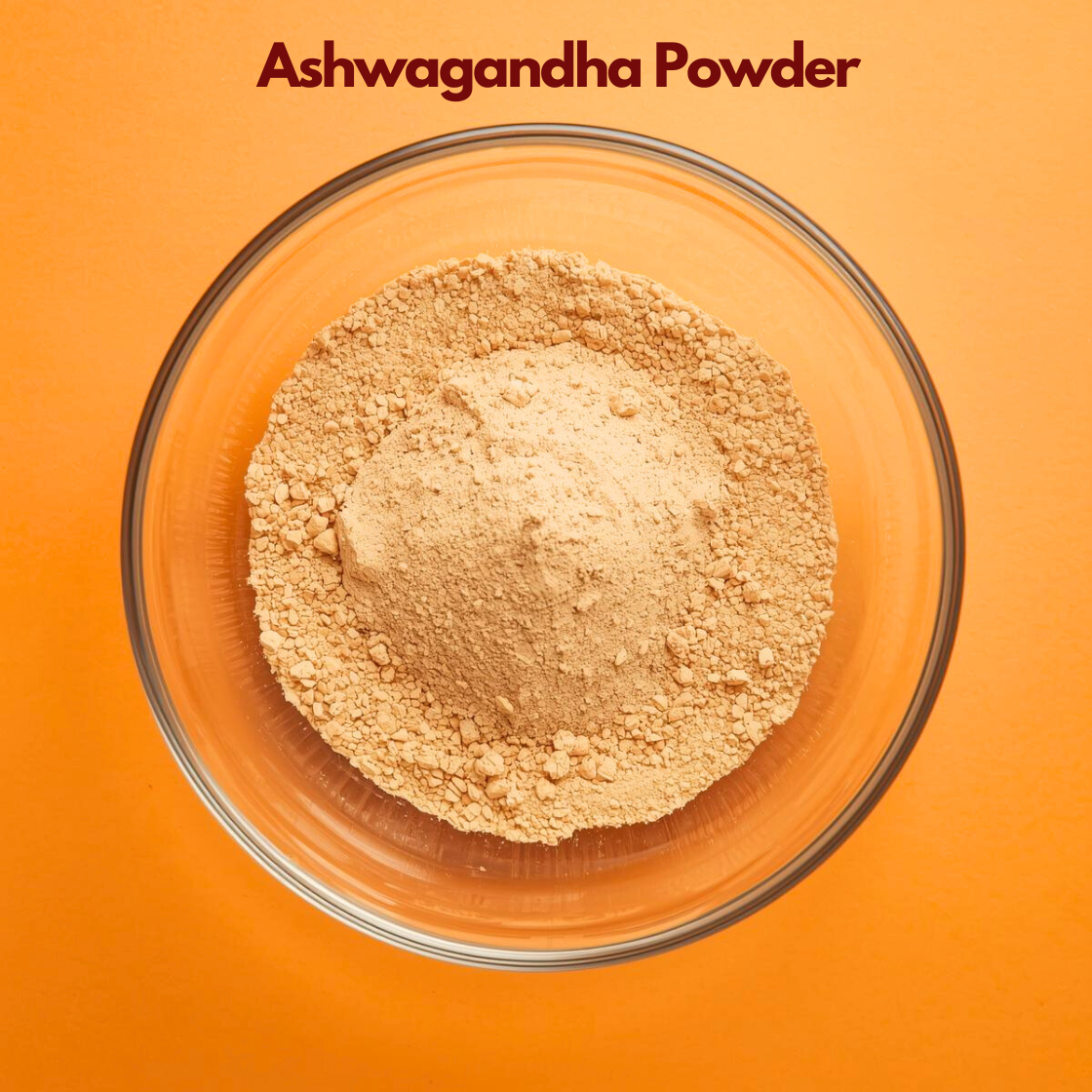 Close up overhead shot of Ashwagandha Powder in a transparent bowl, displaying fine light brown herbal powder with slightly grainy texture on an orange backdrop. Traditional Ayurvedic  powder used in herbal supplements and natural face mask blends.