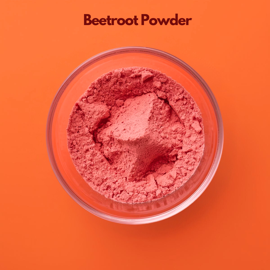 Overhead close up of Beetroot Powder in a clear glass bowl against a bright orange backdrop, showing vivid deep pink finely milled botanical powder. Natural plant based powder used in cosmetic formulations, lip and skincare blends and herbal beauty products for natural coloring.
