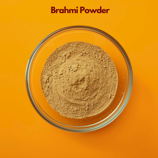 Top view of Brahmi Powder in a transparent glass bowl against a bright orange background, featuring finely milled light brown herbal powder. Ayurvedic botanical powder used in herbal hair masks, scalp nourishment treatments and natural cosmetic formulations for healthy hair care.