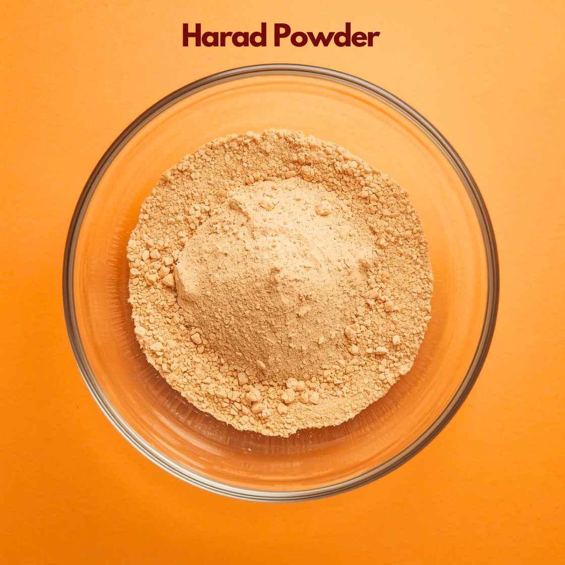 Top angle view of Harad Powder placed in a clear glass bowl, featuring finely milled beige brown herbal powder against a bold orange background. Botanical powder used in herbal face mask formulations and natural skincare applications.