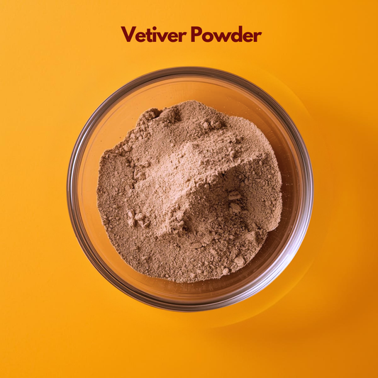 Top view of Vetiver Powder in a transparent bowl, showing fine light brown herbal powder with slightly coarse texture against a bright orange background. Aromatic Ayurvedic botanical powder used in cooling face packs, natural skincare and herbal cosmetic formulations.