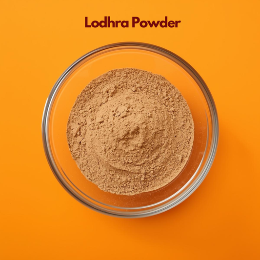  Close up image of Lodhra Powder in a transparent glass bowl, displaying its fine beige brown texture on a vibrant orange backdrop. Traditional Ayurvedic herbal powder used in natural skincare formulations for skin toning, oil balance and herbal face mask applications.