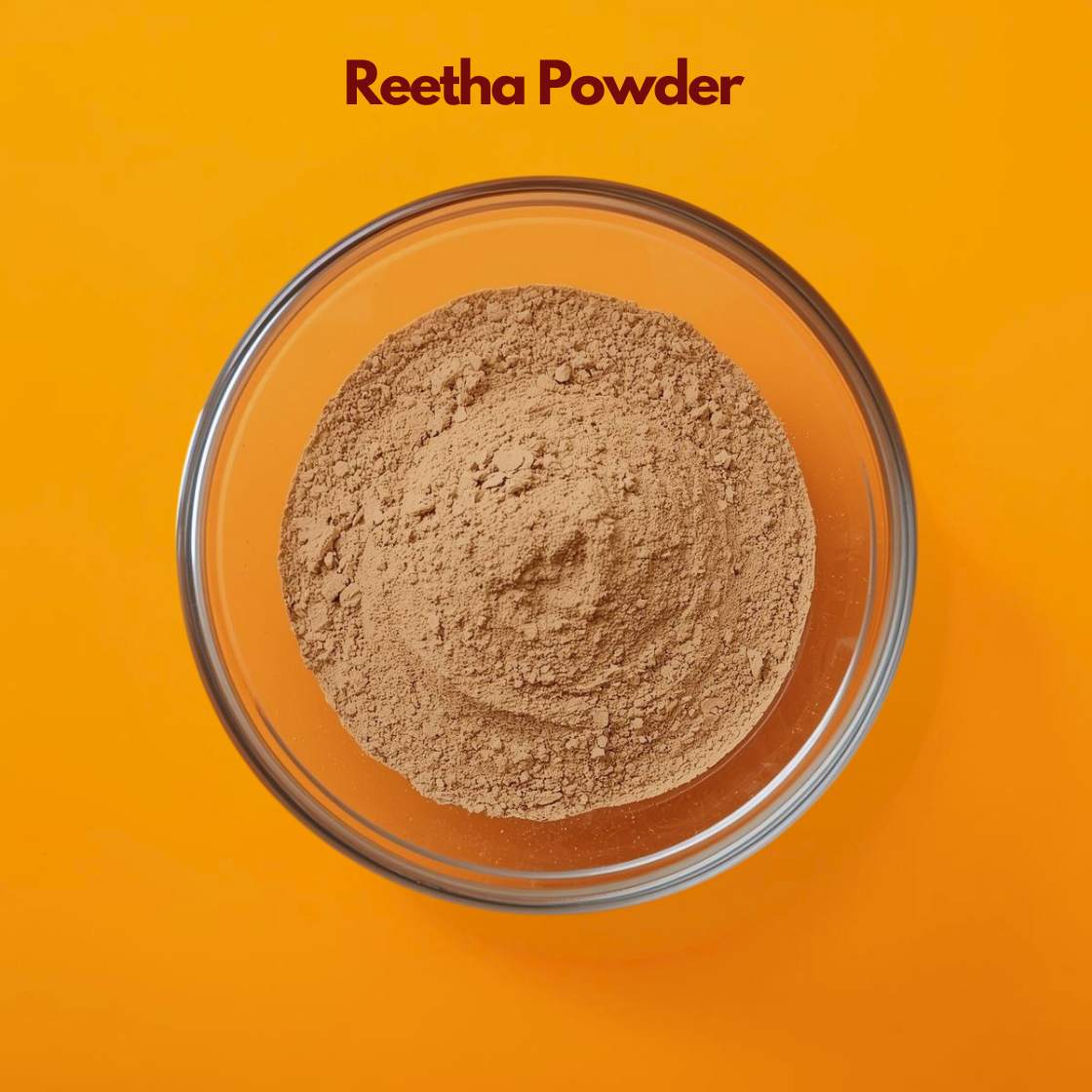 Top view of Reetha Powder in a transparent glass bowl placed on a vibrant orange background, showing finely ground light brown herbal powder with soft, slightly coarse texture. Natural  powder used in hair care formulations for gentle cleansing, scalp purification and herbal shampoo blends.