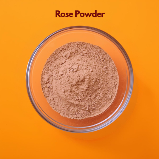 Overhead close up of Rose Powder in a clear glass bowl placed on an orange background, displaying finely milled soft pink floral powder with smooth texture. Natural rose petal powder used in face masks, skin soothing treatments and herbal cosmetic formulations.