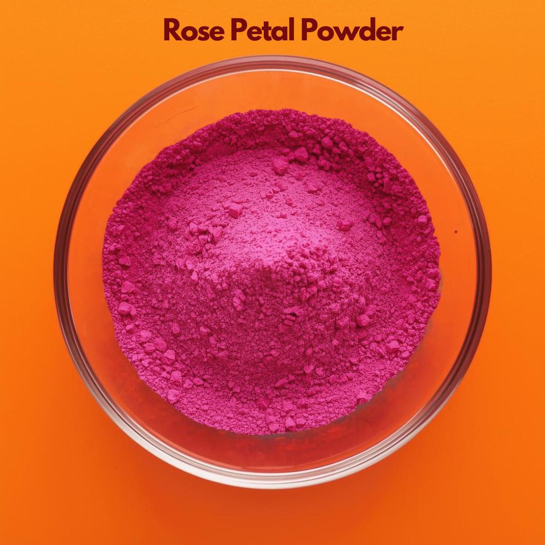 Top angle close up of Rose Petal Powder in a transparent glass bowl, displaying vibrant pink finely ground floral powder against an orange backdrop. Natural botanical powder used in face masks, skin brightening treatments and herbal cosmetic formulations.

