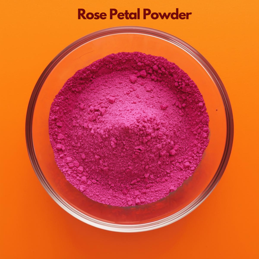 Top angle close up of Rose Petal Powder in a transparent glass bowl, displaying vibrant pink finely ground floral powder against an orange backdrop. Natural botanical powder used in face masks, skin brightening treatments and herbal cosmetic formulations.
