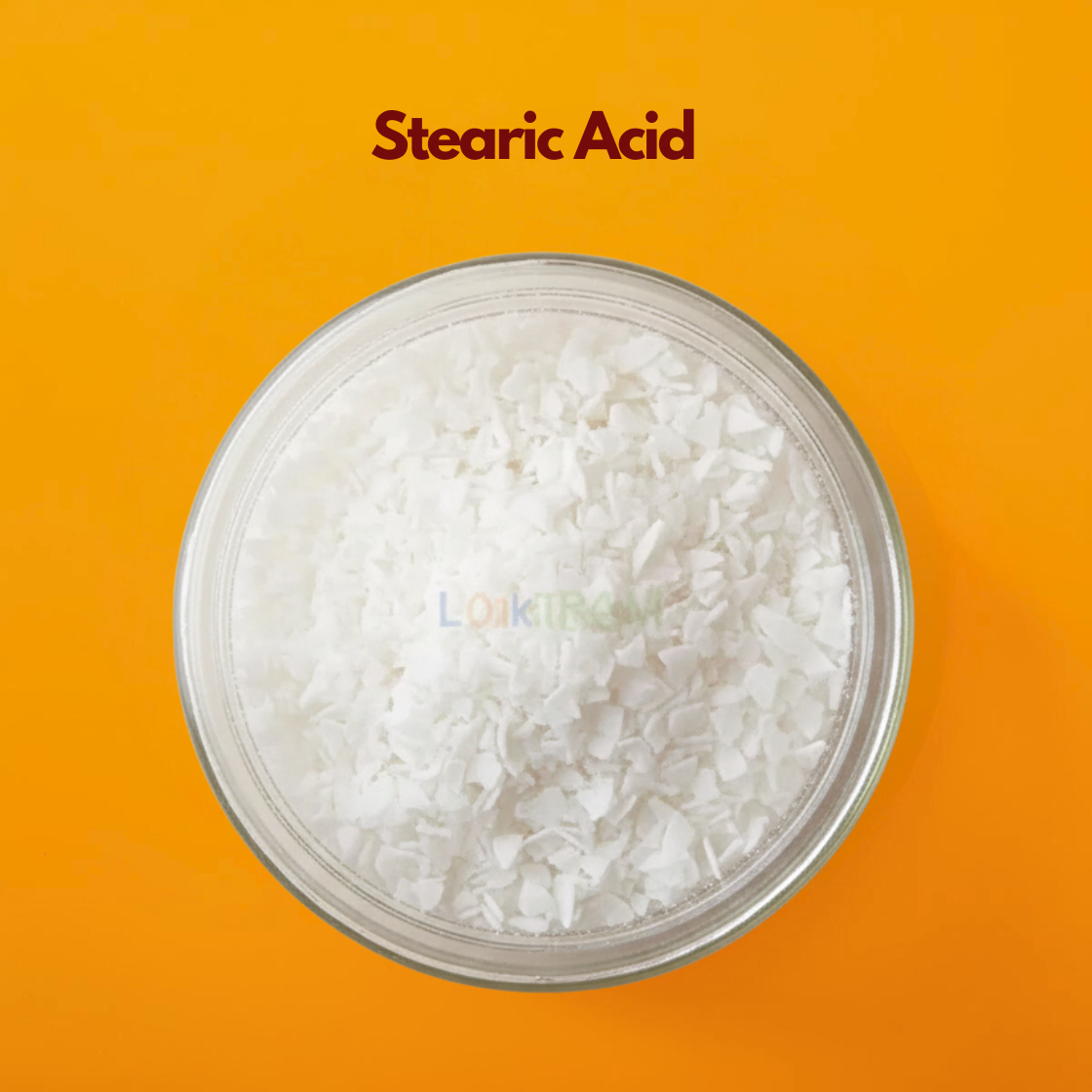 Circular close up view of fine white stearic acid granules labeled "Stearic Acid" placed on a bright orange background. Stearic acid is a fatty acid widely used in cosmetic formulations as an emulsifier thickening agent and stabilizer in creams and lotions.