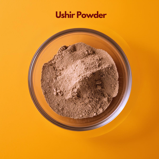  Overhead image of Ushir Powder placed in a clear glass bowl, revealing light brown finely milled herbal powder on a vibrant orange surface. Traditional Ayurvedic cooling herb powder used in natural skincare masks and botanical cosmetic blends.